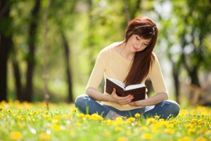 Young woman reading a book in the park with flowers